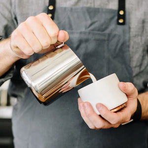 Barista nalewa mleko z polerowanego dzbanka ze stali nierdzewnej, część akcesoriów do Espresso i dzbanek do mleka, wszystko o kawie.